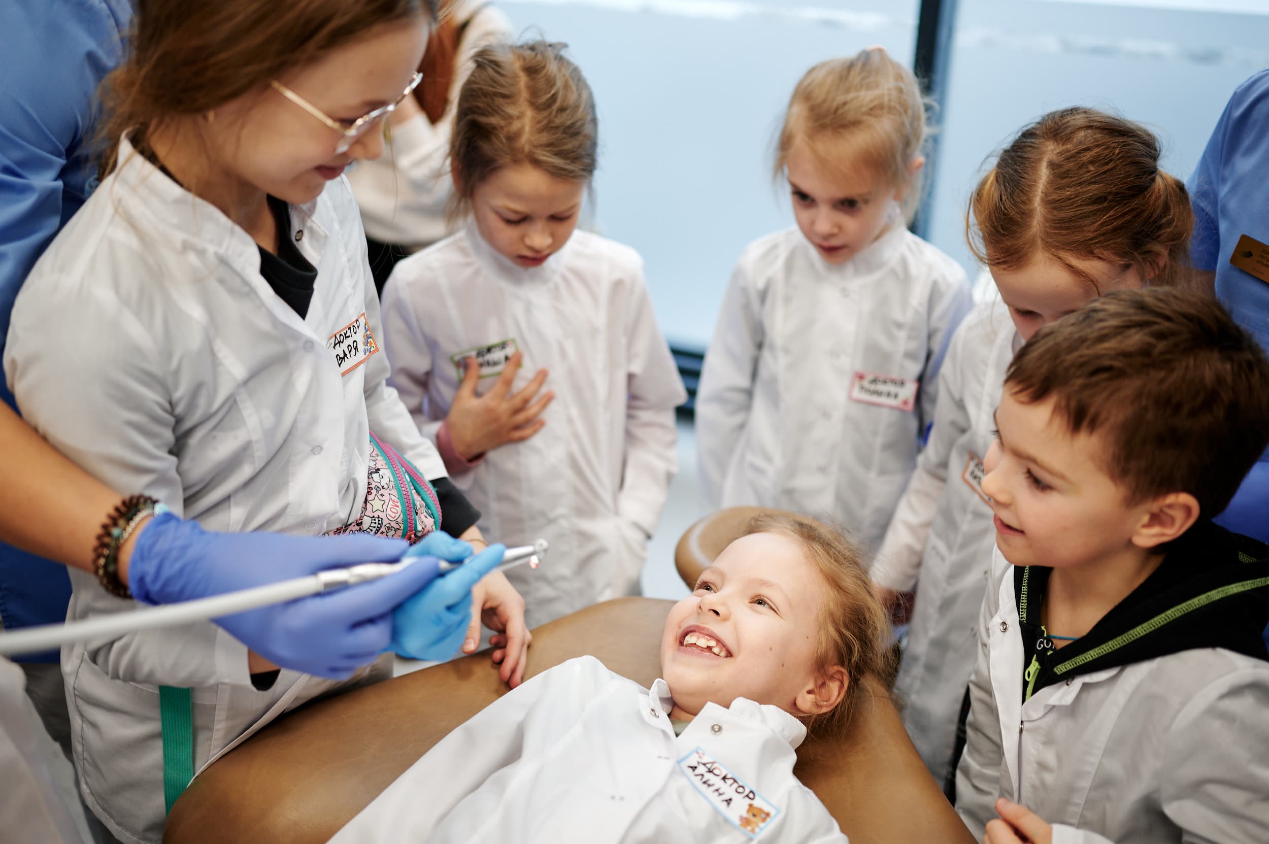 Дети в белых халатах с зубным врачом